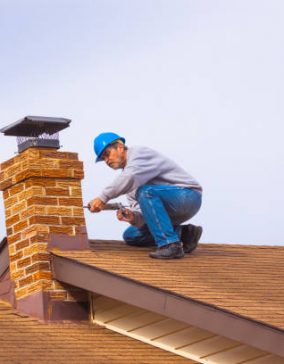 Contractor Builder with blue hardhat on the roof caulking chimney